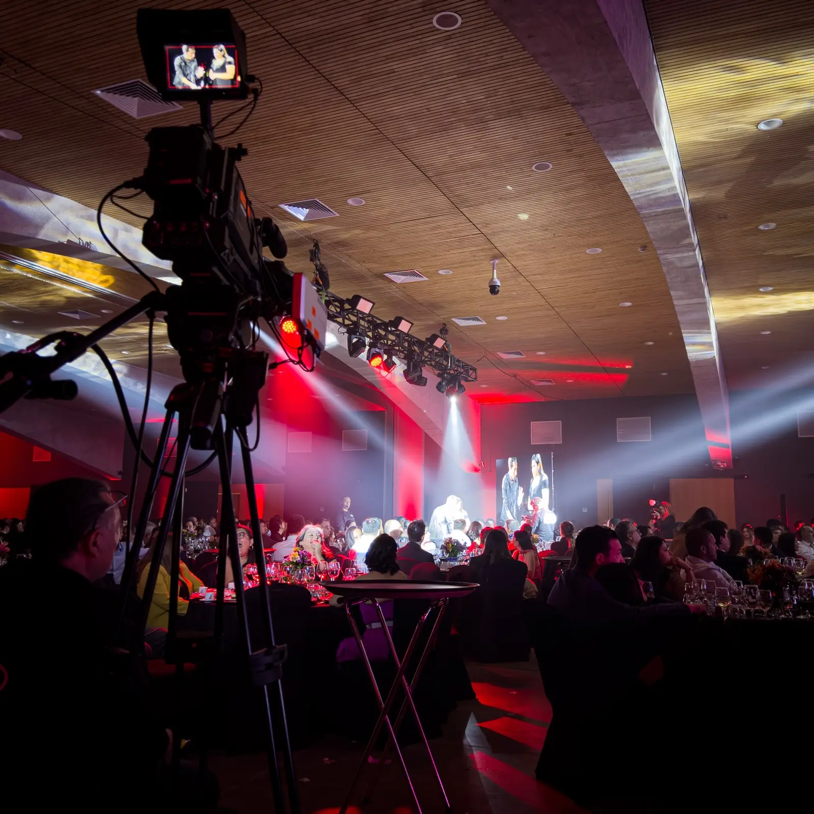 Cámara broadcast en trípode transmitiendo un evento en vivo ante el público